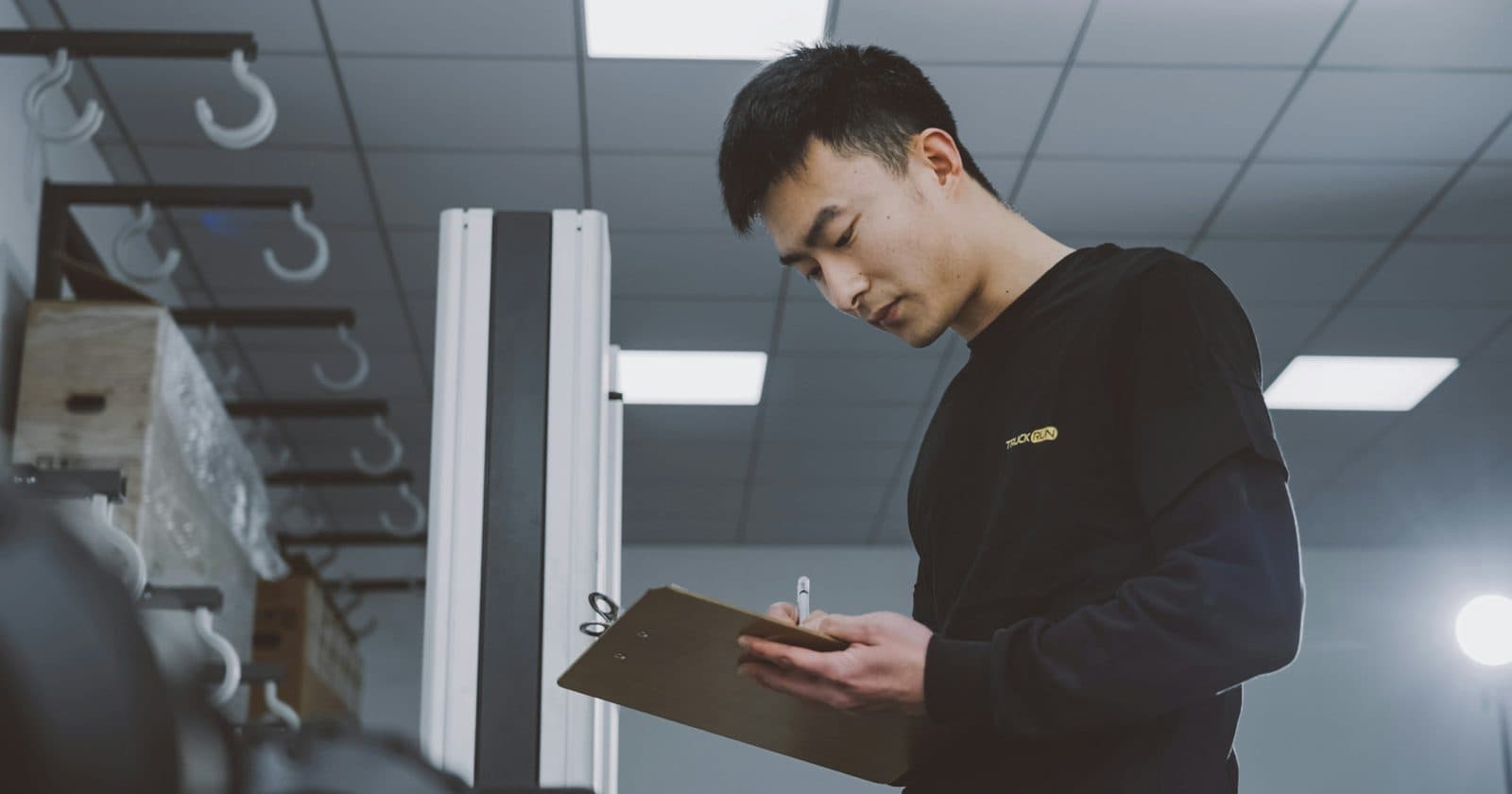 A technician holding a clipboard while checking equipment in a warehouse